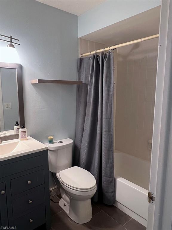 Image 2: Bathroom with vanity, dark tile patterned floors, and shower / bathtub combination with curtain