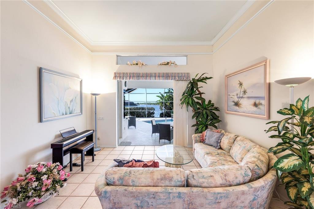 Image 4: Living area with light tile patterned flooring and crown molding
