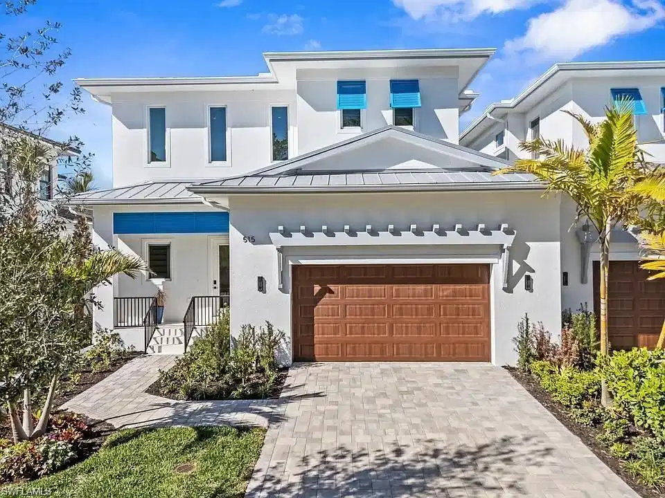 Image 1: Contemporary residence featuring a white stucco exterior with a gray metal roof and blue architectural accents