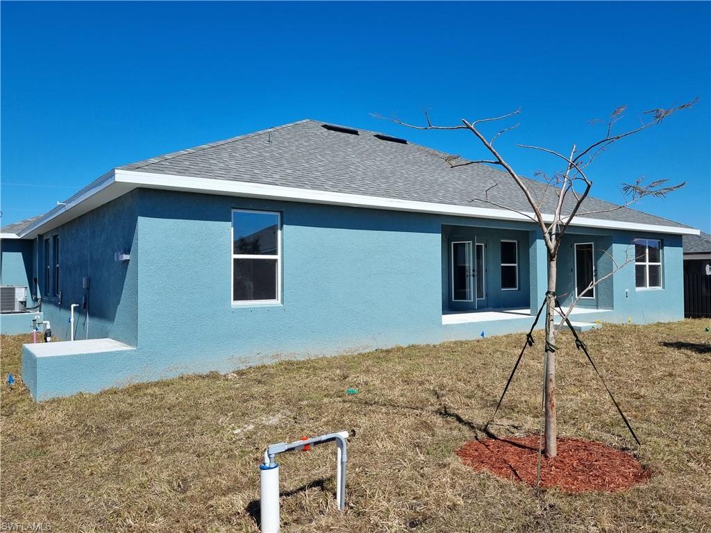 Image 2: Rear view of house featuring stucco siding, a lawn, a patio area, and roof with shingles