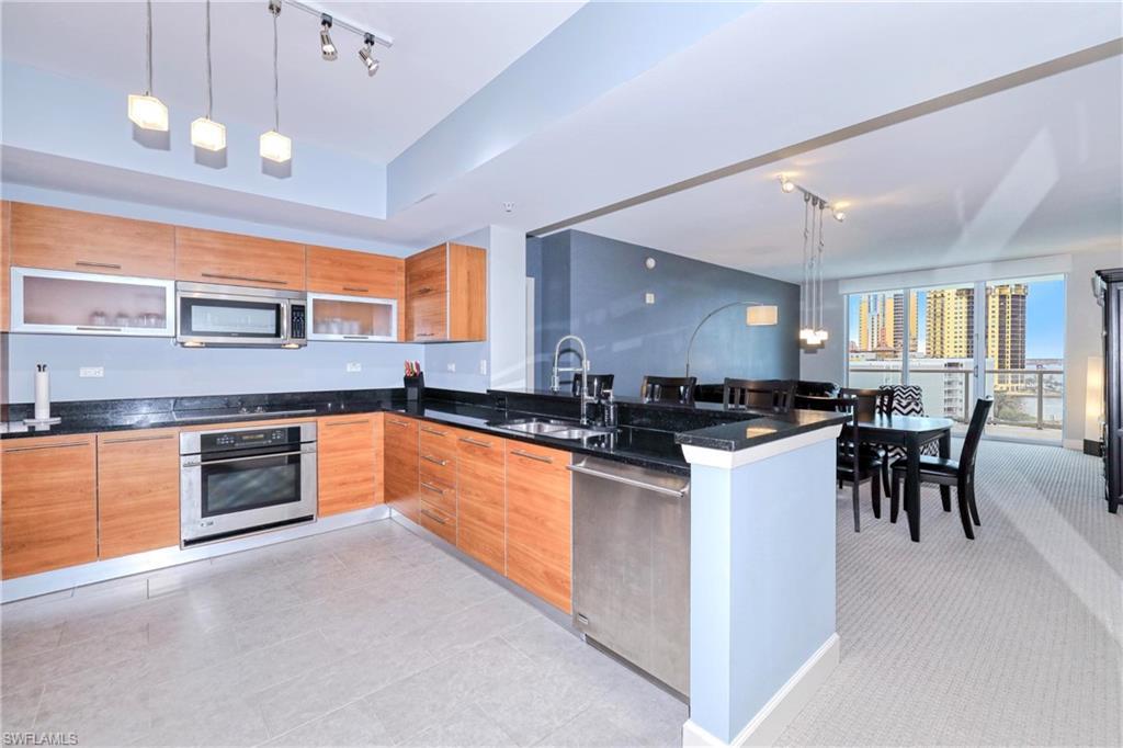 Image 3: Kitchen with kitchen peninsula, decorative light fixtures, track lighting, appliances with stainless steel finishes, and sink