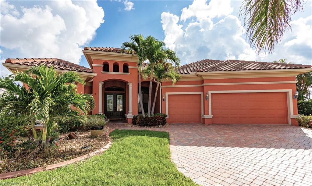 Image 2: Mediterranean-style exterior featuring a tile roof, stucco finish, paver driveway, arched entryway, and mature landscaping