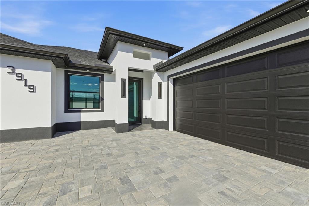 Image 3: Property entrance featuring decorative driveway and stucco siding