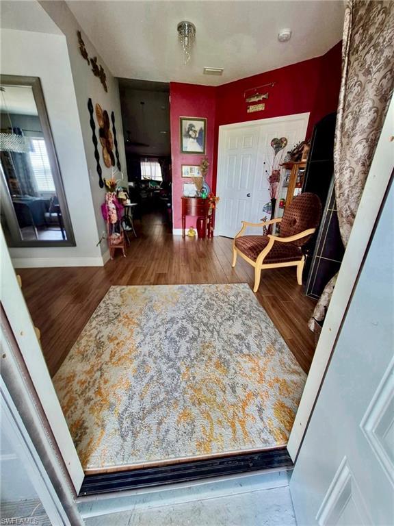 Image 4: Entryway featuring wood-finish flooring, a white paneled door, and a decorative pendant light fixture