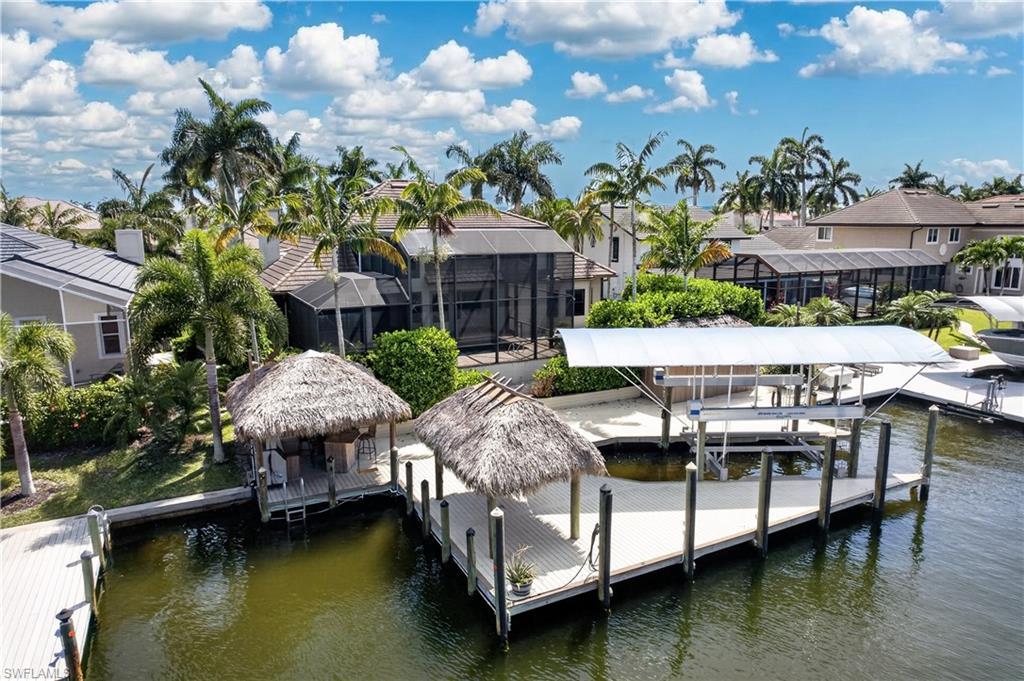Image 3: The property features waterfront access with a private dock, two covered tiki-style structures, and a boat lift