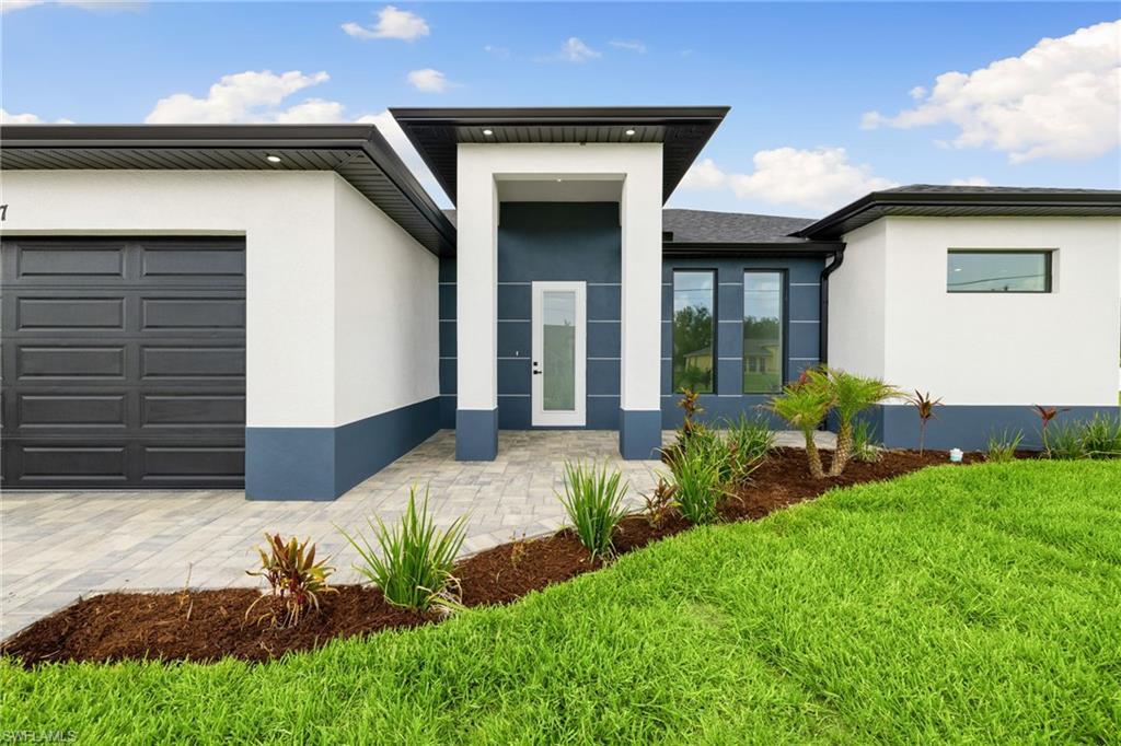 Image 4: View of front facade with stucco siding, a front lawn, and a garage