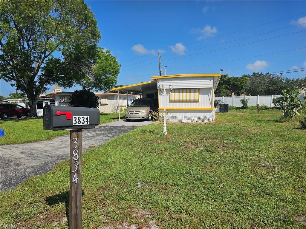 Image 2: View of front of house with an attached carport and asphalt driveway