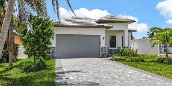 Image 2: Prairie-style home with stone siding, an attached garage, a tile roof, decorative driveway, and stucco siding