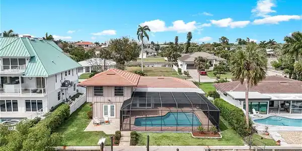 Image 2: Back of property with a patio, an outdoor pool, a lanai, a water view, and a lawn