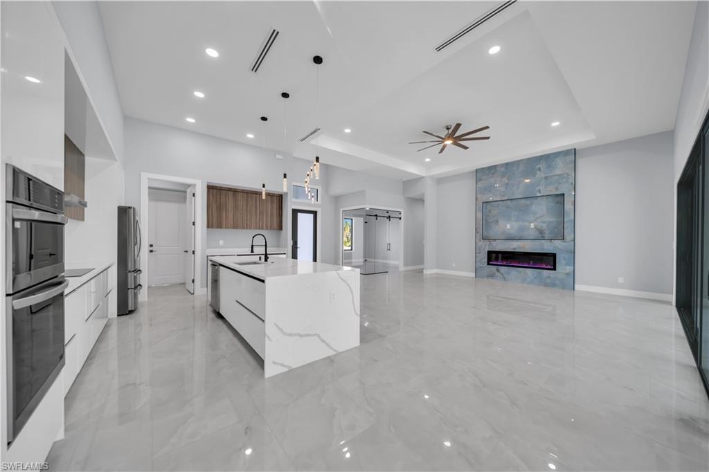Image 3: Kitchen with modern cabinets, decorative light fixtures, recessed lighting, light stone counters, and a ceiling fan