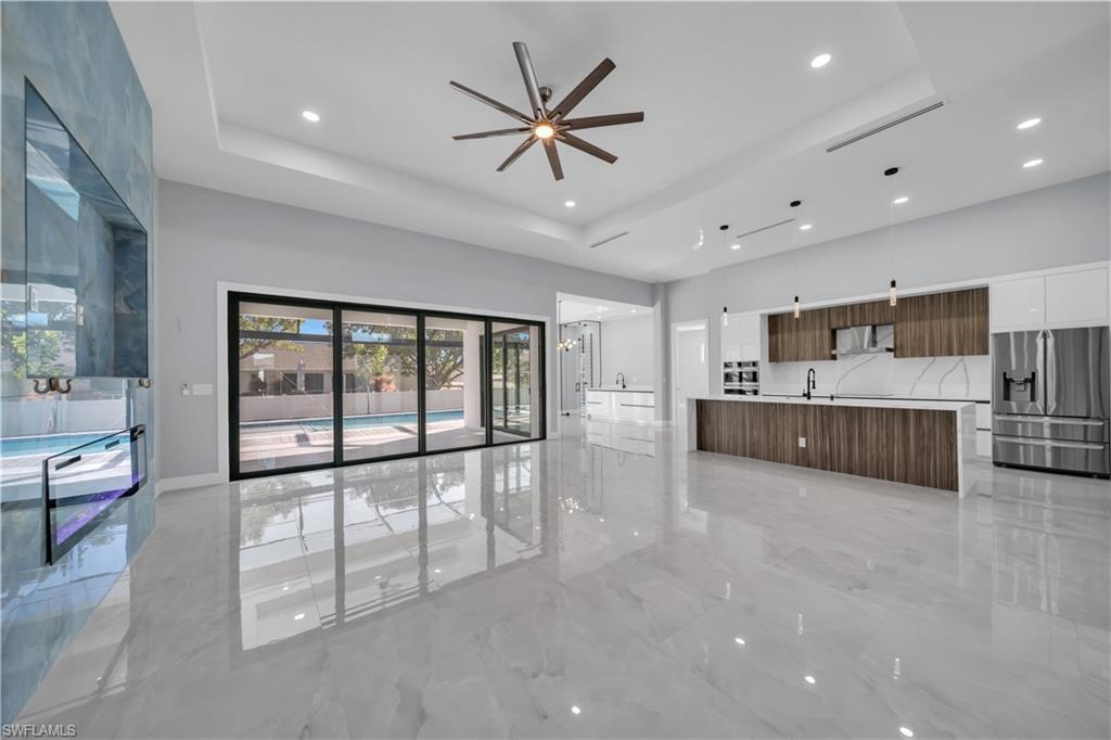 Image 4: Unfurnished living room with light marble finish flooring, a ceiling fan, a raised ceiling, recessed lighting, and a towering ceiling
