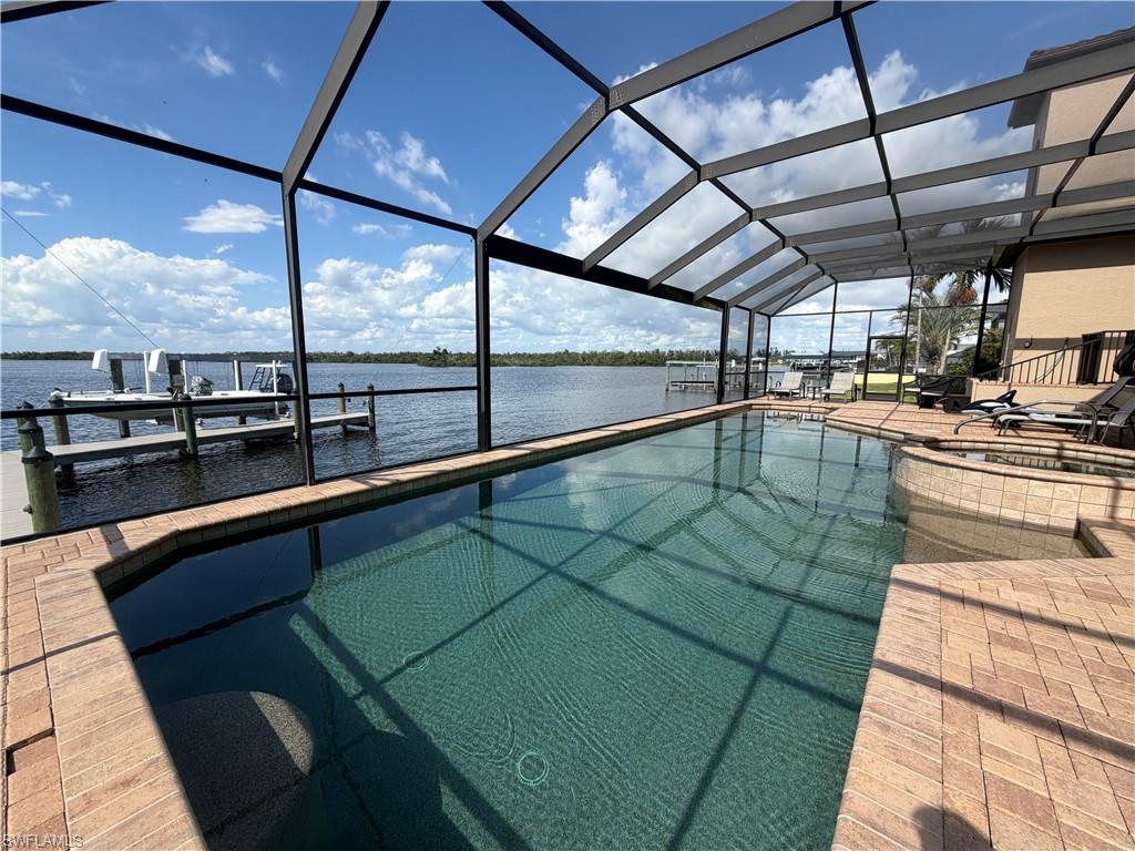 Image 2: Screened lanai featuring a swimming pool, integrated spa, and brick paver decking