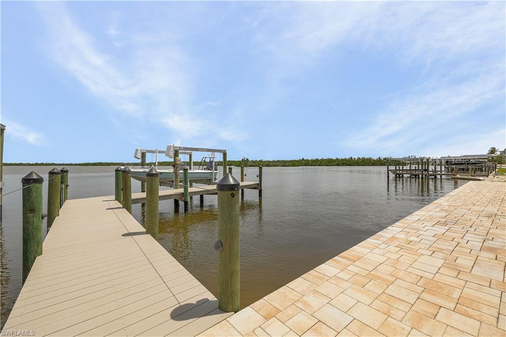 Image 3: Waterfront property featuring a composite deck dock, a boat lift, and a paver decking behind home