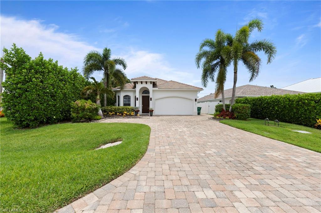 Image 2: Front exterior featuring a white stucco facade, arched entryway, and a paver driveway
