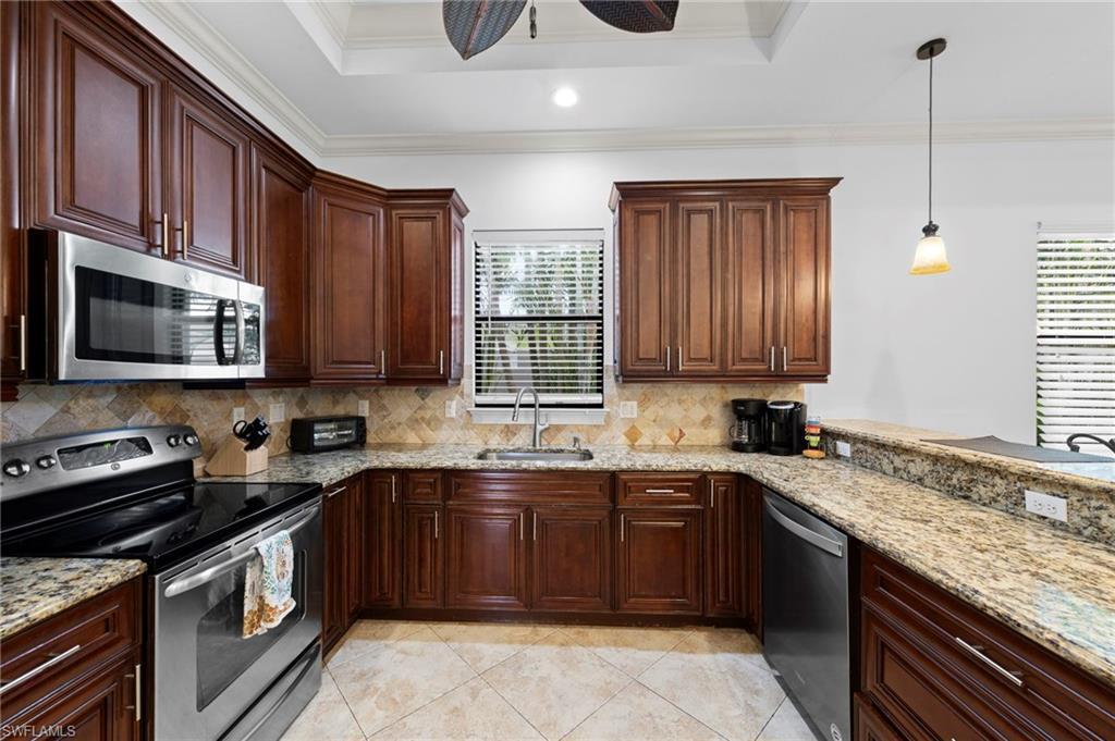 Image 4: Kitchen featuring wood cabinetry, stainless steel appliances, granite countertops, and a tile backsplash