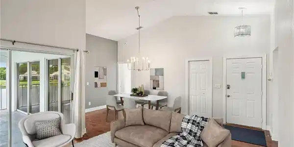 Image 3: Living area with high vaulted ceiling, a chandelier, wood finished floors, and a water view