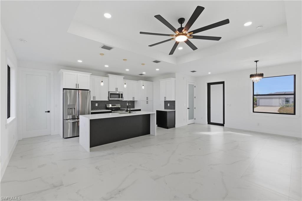 Image 4: Kitchen with a tray ceiling, open floor plan, decorative light fixtures, and recessed lighting