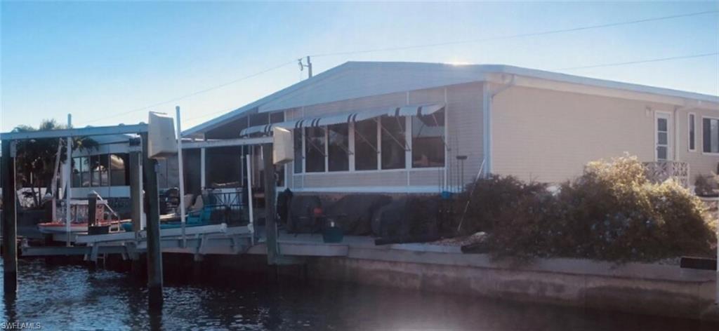 Image 2: Rear view of house featuring a water view, boat lift, and a sunroom