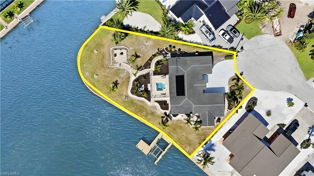 Image 4: Aerial view of property and surrounding area featuring property parcel outlined and a large body of water - Virtually Edited Image
