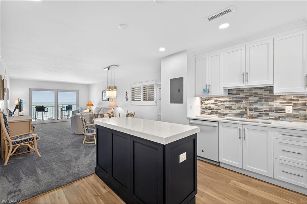 Image 2: Kitchen with open floor plan, white dishwasher, light stone counters, light wood finished floors, and dual tone cabinetry