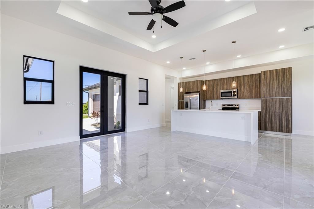 Image 4: Unfurnished living room featuring a raised ceiling, light marble finish floors, recessed lighting, and ceiling fan