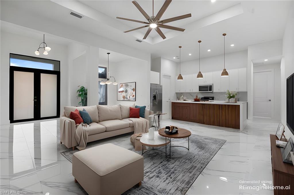 Image 2: Living room with ceiling fan with notable chandelier and a tray ceiling