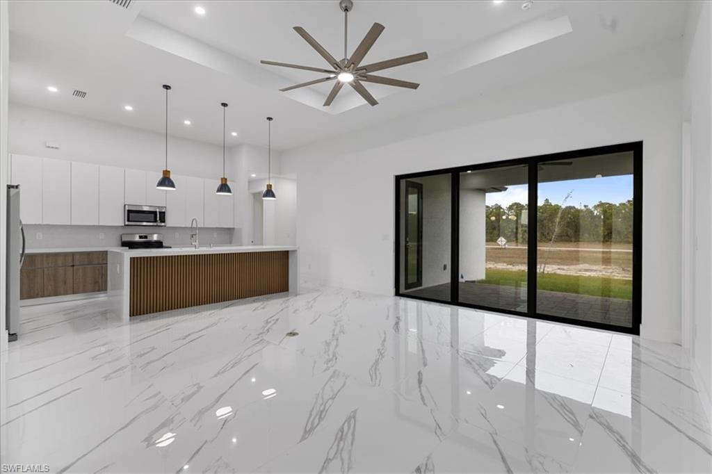 Image 3: Kitchen with a raised ceiling, an island with sink, white cabinets, and stainless steel appliances