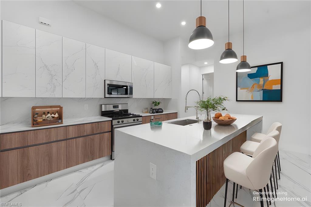 Image 4: Kitchen with an island with sink, a breakfast bar area, appliances with stainless steel finishes, pendant lighting, and sink