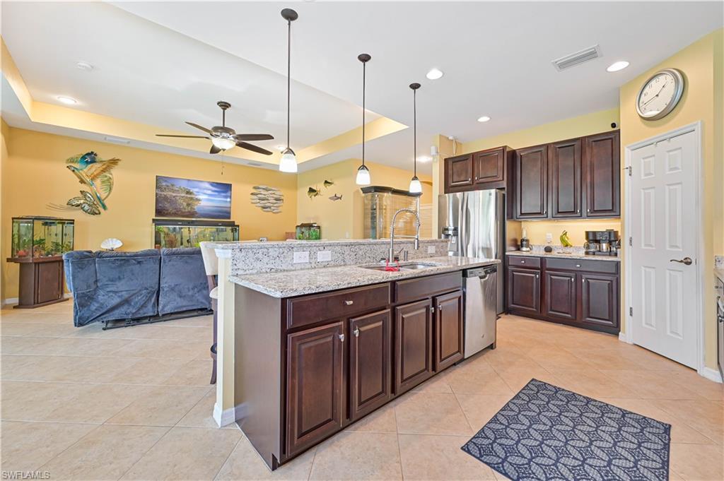 Image 2: Kitchen with stainless steel appliances, a tray ceiling, sink, and hanging light fixtures