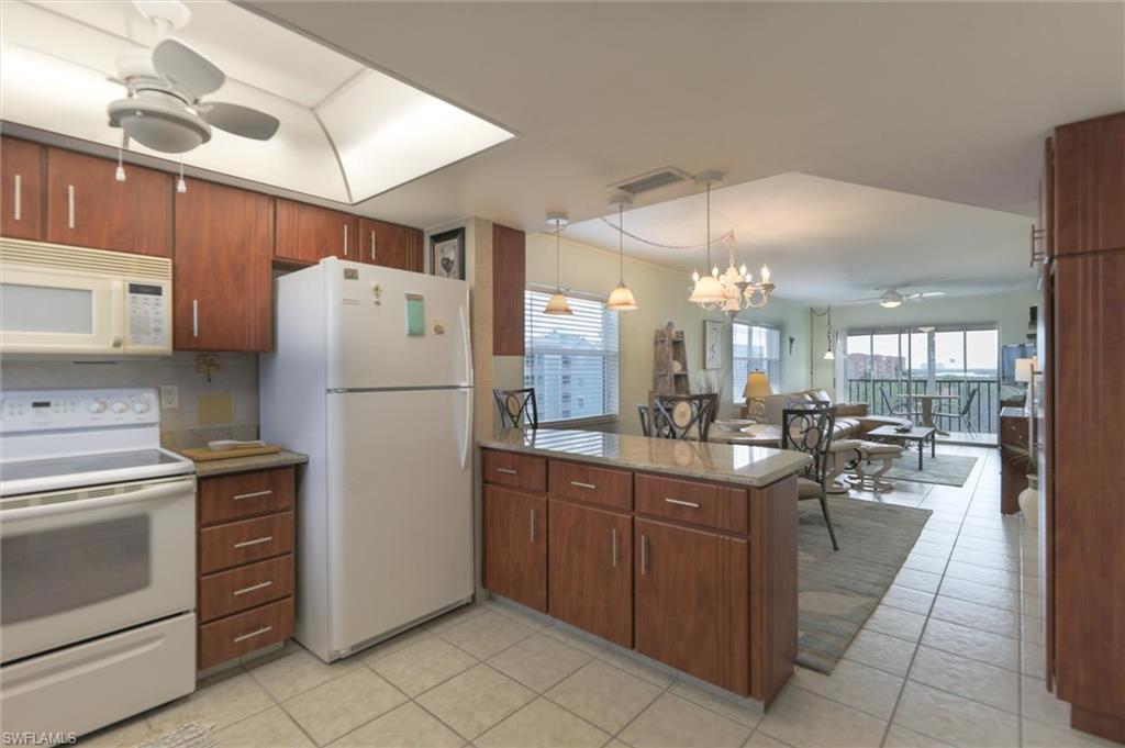 Image 3: Kitchen with pendant lighting, white appliances, light tile floors, and ceiling fan with notable chandelier