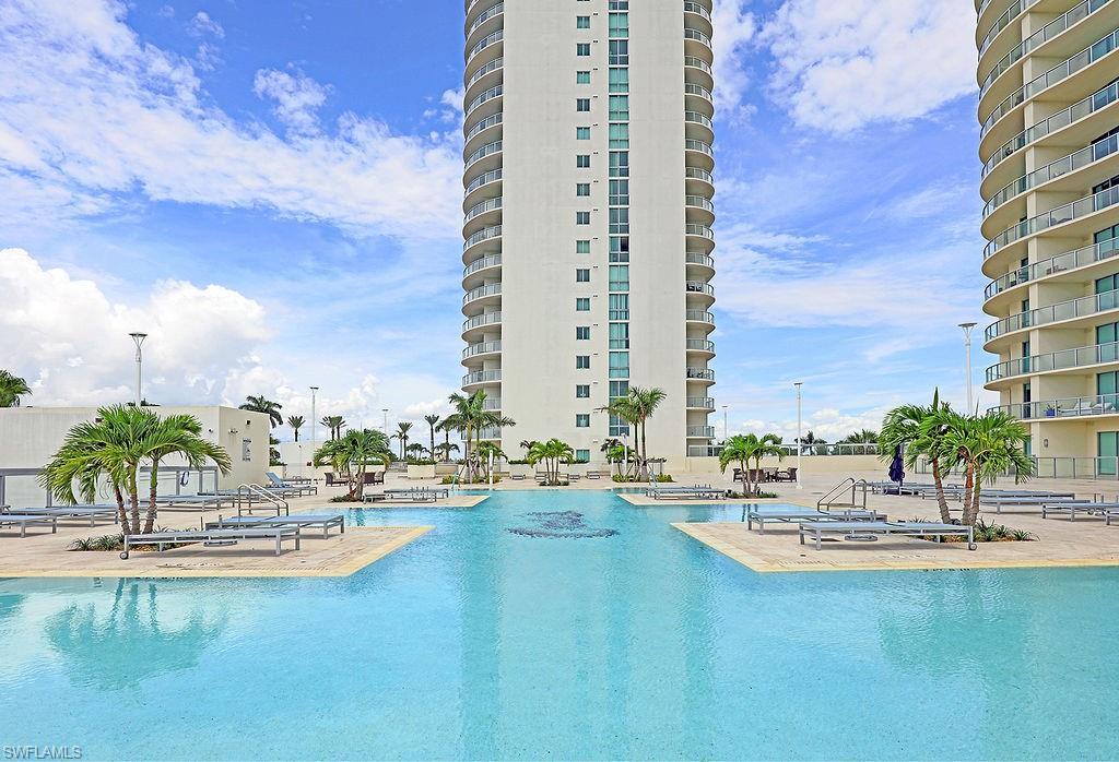 Image 4: Expansive resort-style pool featuring multiple swimming areas, integrated lounging platforms, and surrounding palm trees