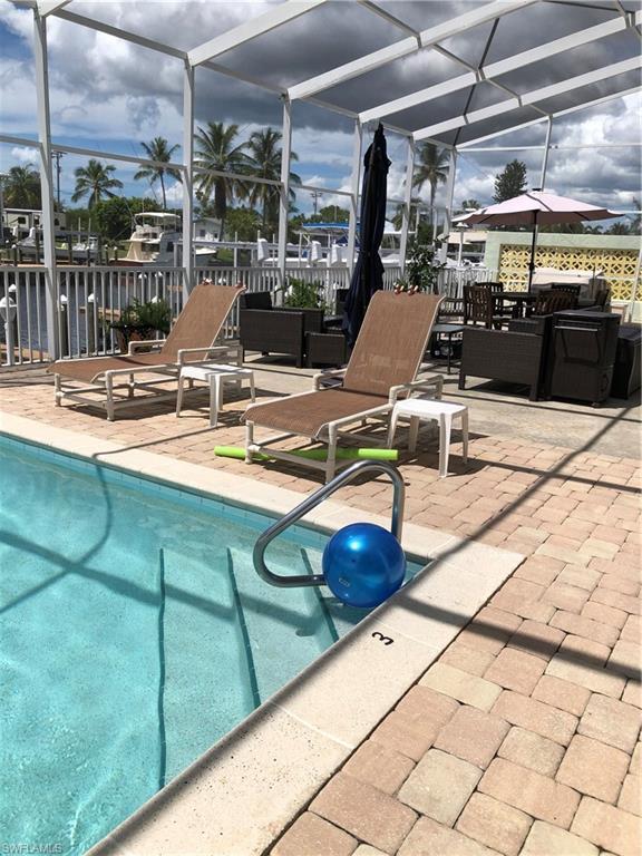 Image 1: Outdoor pool featuring screened enclosure and a patio area