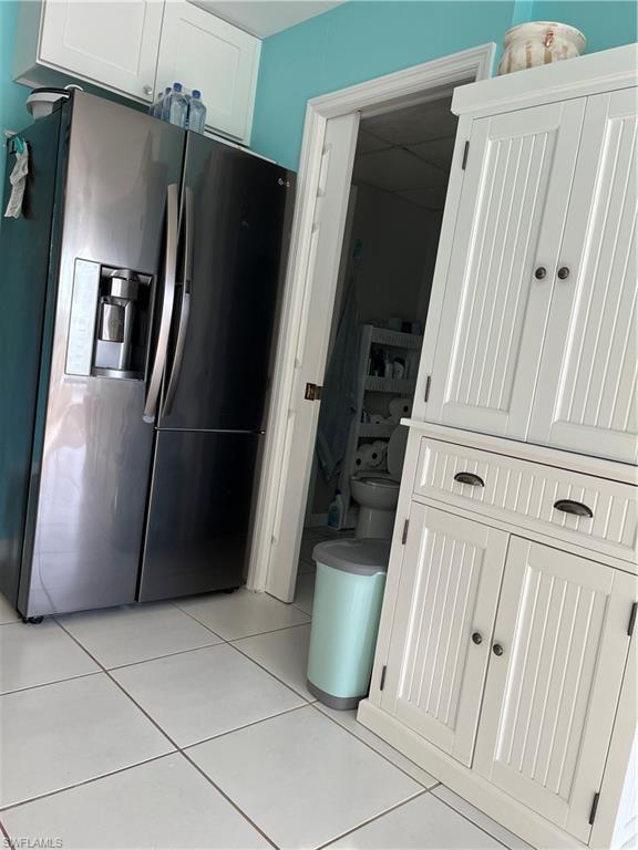Image 2: Kitchen featuring white cabinetry, refrigerator, and light tile patterned floors