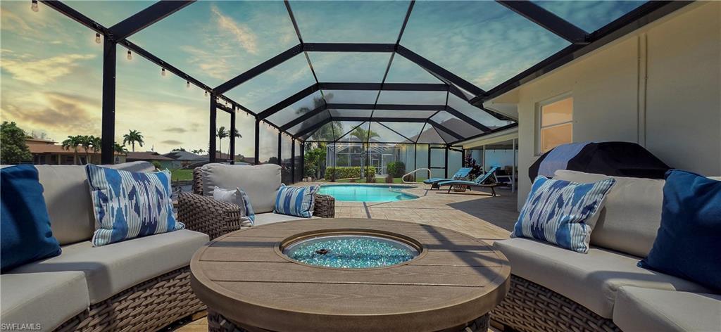 Image 1: Screened lanai featuring a built-in fire pit, spacious paver patio, in-ground swimming pool, and string lighting