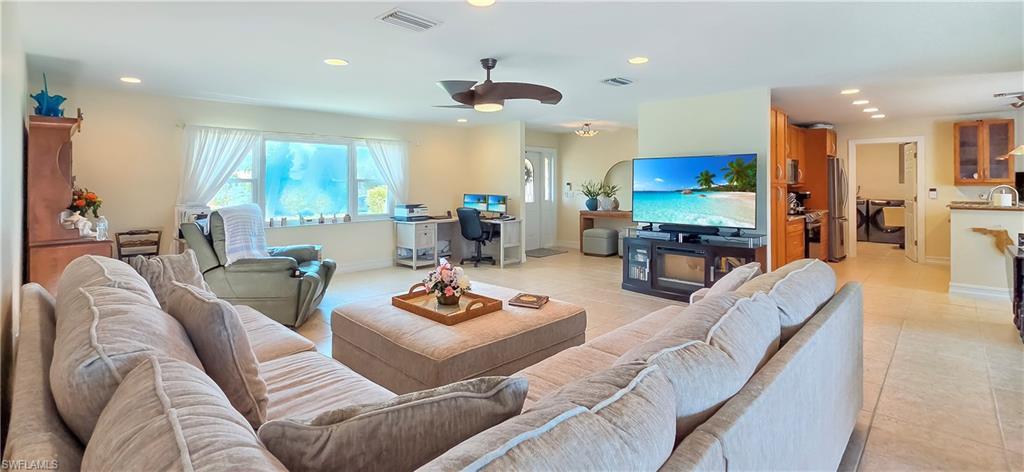 Image 4: Open-concept living area with neutral tile flooring, recessed lighting, and a ceiling fan