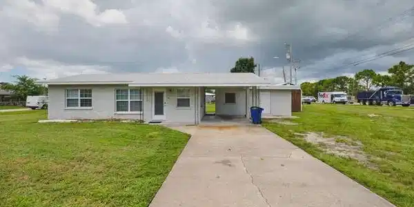 Image 2: View of front facade featuring a front lawn, a carport, concrete driveway, and a porch
