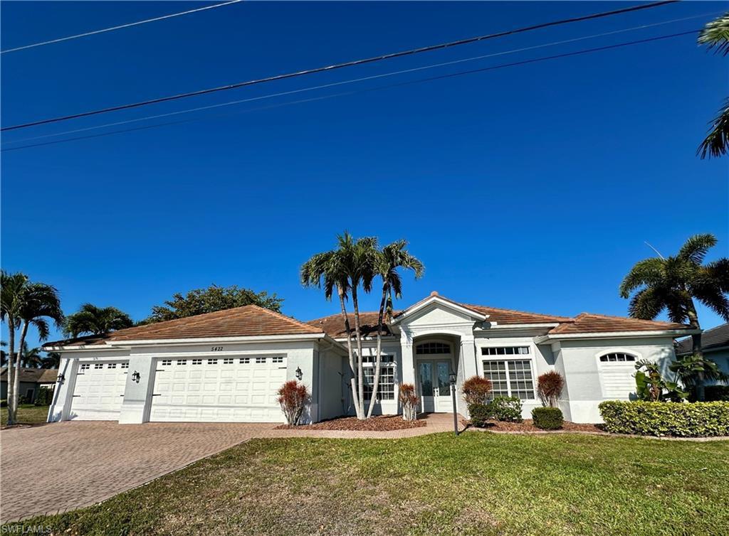 Image 4: View of newly repainted complete THREE-LOT, THREE CAR GARAGE, Front elevation with Designed Palms and Shruberry and Pavered Three Car Wide Driveway and Pavered Walkway to Entry w/Multi Colored Volcanic Mulch