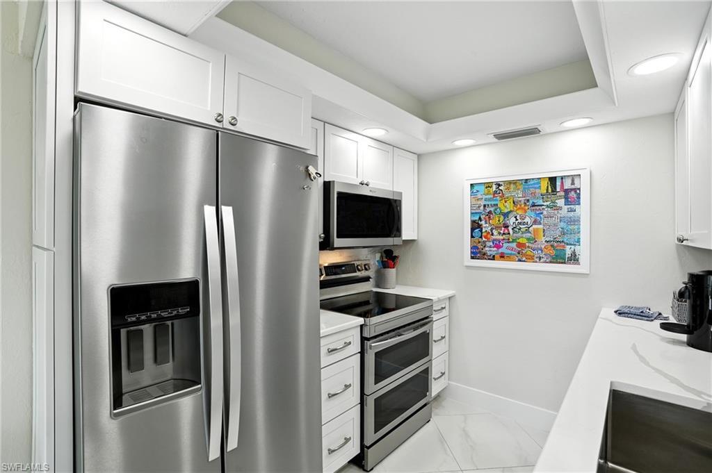 Image 4: Kitchen featuring stainless steel appliances, white cabinets, light stone counters, light marble finish flooring, and recessed lighting