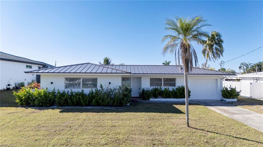 Image 1: Ranch-style home featuring a garage, a front lawn, a metal roof, and concrete driveway