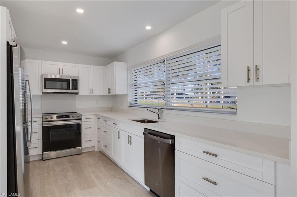 Image 2: Kitchen featuring stainless steel appliances, white cabinets, light wood-style floors, recessed lighting, and light stone countertops