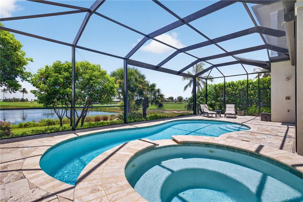 Image 4: Screened lanai featuring a freeform pool and integrated spa