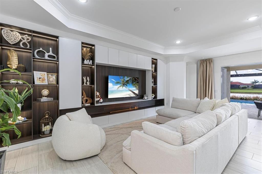Image 1: Living room featuring built in features, ornamental molding, a tray ceiling, and recessed lighting