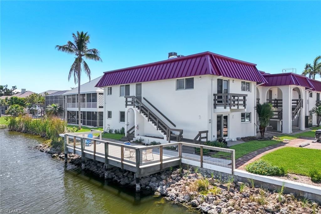 Image 2: Waterfront property featuring a private wood dock with metal railings, white exterior, purple metal roof, and multiple balconies