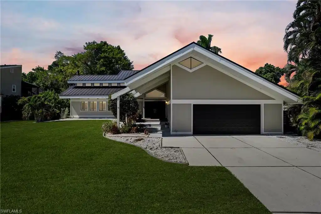 Image 1: Contemporary architecture featuring a prominent gable roofline, light-toned exterior siding, and a dark garage door