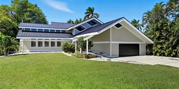 Image 2: Contemporary exterior with a dark metal roof and light-toned siding