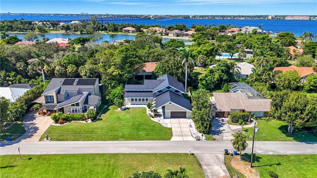 Image 4: Waterfront neighborhood featuring a modern residence with an attached garage, solar panels, and a manicured lawn