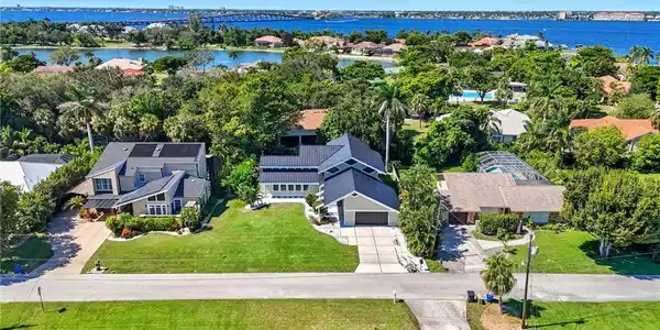 Image 4: Waterfront neighborhood featuring a modern residence with an attached garage, solar panels, and a manicured lawn