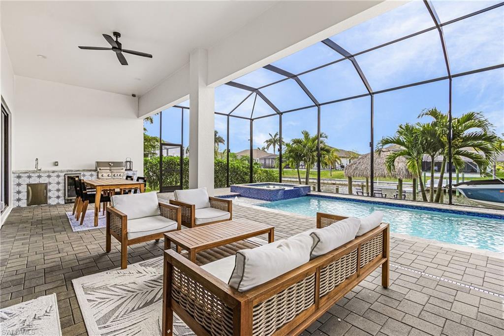 Image 4: Screened lanai featuring a swimming pool, integrated spa, and an outdoor kitchen with a built-in grill and sink