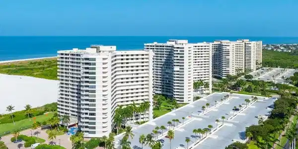 Image 2: Multi-story residential buildings with multiple balconies, adjacent to a wide sandy beach and ocean