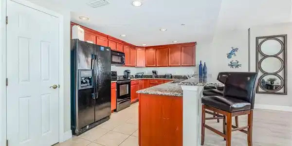 Image 4: Kitchen with black appliances, a kitchen bar, a peninsula, light stone countertops, and a textured ceiling